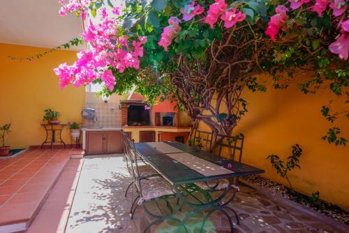 a table and chairs in a kitchen with pink flowers at Il Piccolo Giardino rooms & breakfast in Villasimius