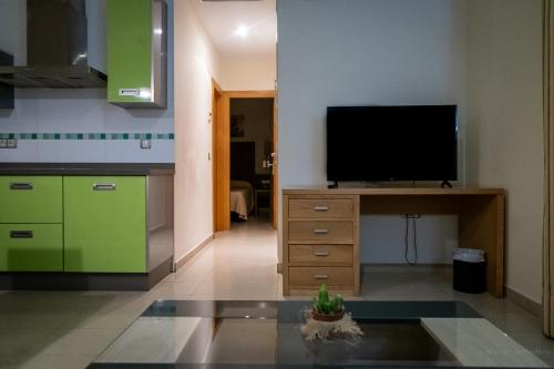 a living room with a tv on a stand with a kitchen at Hotel Macami in El Carpio