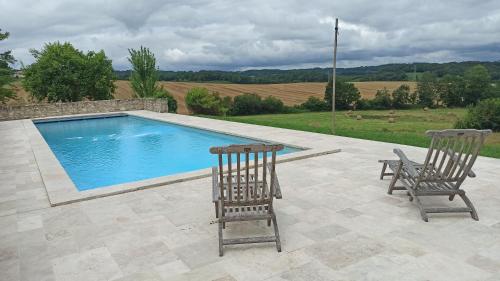 two chairs sitting next to a swimming pool at Maison de campagne avec accès à une piscine partagée - Linge non fourni in Beaugas