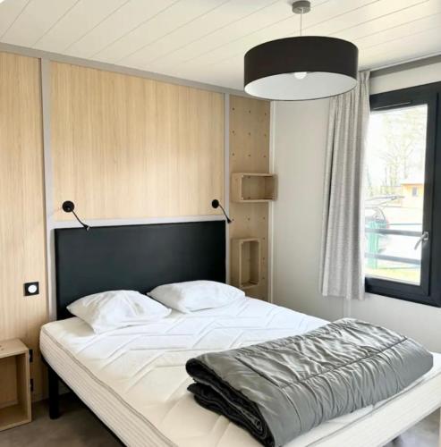 - une chambre avec un grand lit blanc et une tête de lit noire dans l'établissement Chalet à louer - 52m2 - Landes, à Saint-Geours-de-Maremne