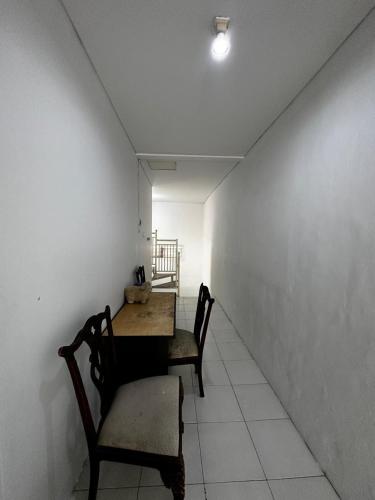 a table and chairs in a room with a white wall at AKKA Sharia Guesthouse in Srondolwetan