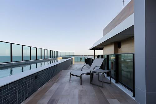 a balcony with two chairs and a view of the water at Flat pé na areia na praia de Porto de Galinhas próximo as piscinas naturais. in Porto De Galinhas
