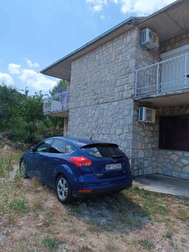 a blue car parked in front of a house at Apartman Tomas in Trebinje