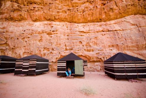 a person sitting in a tent in front of a cliff at Wadi Rum Fire Camp in Wadi Rum