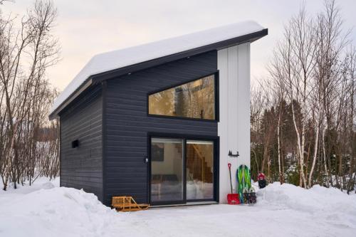a house with a black exterior in the snow at Hebergement du grenier 2 0 in Notre-Dame-des-Monts