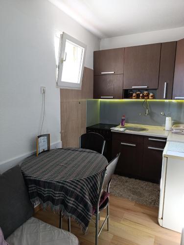 een kleine keuken met een tafel en een gootsteen bij Apartman Maja in Bijeljina