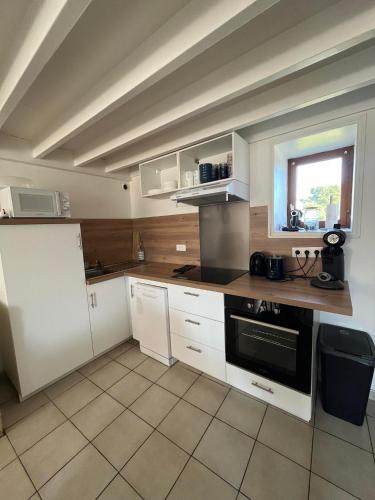 een keuken met witte kasten en een zwarte oven bij Petite maison de La Hague in Beaumont-Hague