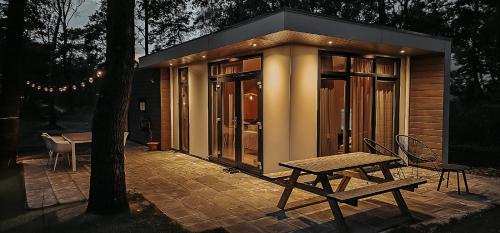a small cabin with a table and a bench on a patio at Elly's Broekhuisje in Haarle