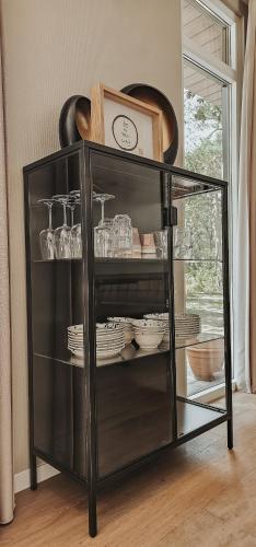 a black shelf with dishes and a clock on it at Elly's Broekhuisje in Haarle