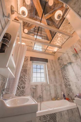 La salle de bains est pourvue d'un lavabo, d'une baignoire et d'une fenêtre. dans l'établissement LA GARENNE Chambre d 'hôtes, à Reilhaguet