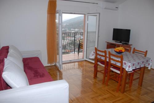Una sala de estar con una mesa y sillas y un televisor. en Apartments Kate, en Senj