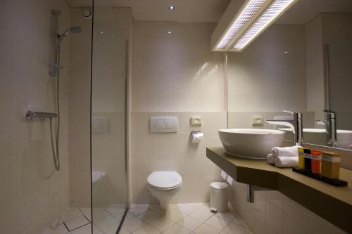 ein Bad mit einer Dusche, einem WC und einem Waschbecken in der Unterkunft Hotel Arrows in Uden