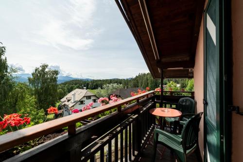 a balcony with a table and chairs and flowers at Kaiserau 1907 in Collalbo