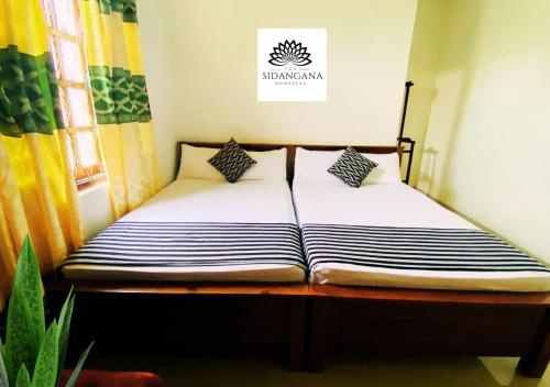 two beds in a small room with a plant at Sidhangana Home Stay in Anuradhapura