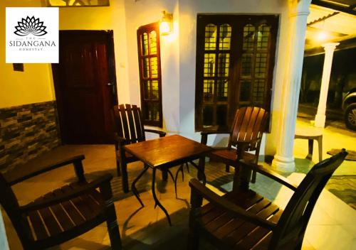 a wooden table and chairs in front of a building at Sidhangana Home Stay in Anuradhapura