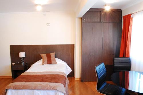 a bedroom with a bed and a desk and a chair at Vitrali Suite in Copiapó