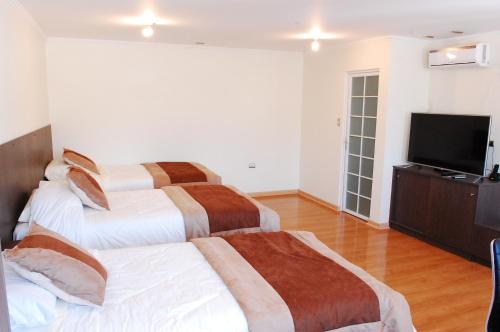 a bedroom with two beds and a flat screen tv at Vitrali Suite in Copiapó