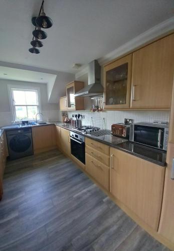 a kitchen with wooden cabinets and a stove top oven at Idyllic Waterside Penthouse in Callander
