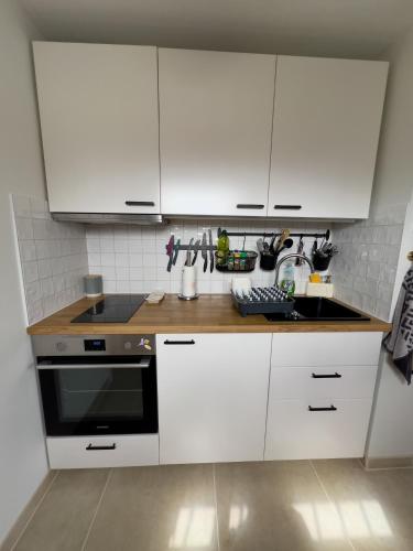 une cuisine avec des armoires blanches et un four à plaques de cuisson dans l'établissement Studio rénové proche de la plage, à Tarnos