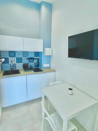 Il comprend une cuisine avec une table blanche et une télévision murale. dans l'établissement 3 Studios indépendants dans villa avec piscine, à Nice