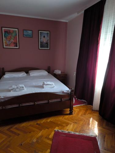 a bedroom with a bed with white sheets and a window at Vila Marija in Podgorica