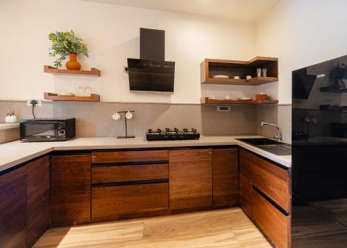 a kitchen with wooden cabinets and a black refrigerator at ORO The Estates, Nandi Hills in Nandigunda