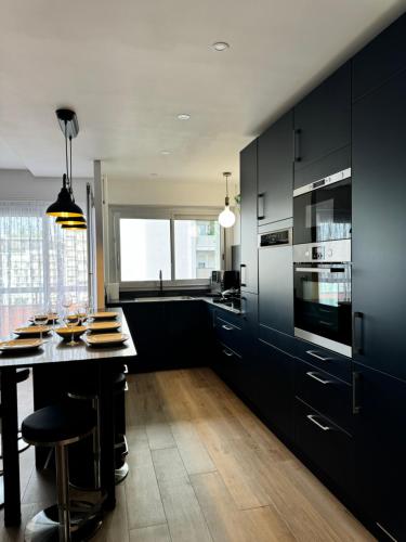 une cuisine avec des armoires noires et une table avec des chaises dans l'établissement Appartement spacieux, à Clichy