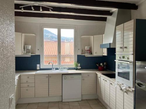 une cuisine avec des armoires blanches et une fenêtre dans l'établissement Belle maison familiale à Millau pour sportifs, à Millau