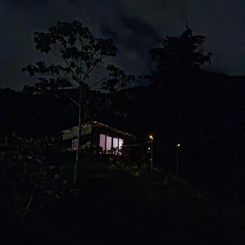 a house at night with a tree in the foreground at Glamping eco descanso la vega Nocaima in Nocaima