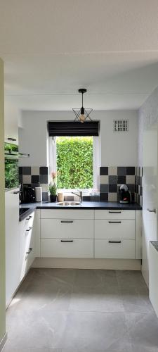 a white kitchen with a sink and a window at Evergreen wellness met sauna & hottub in Ewijk