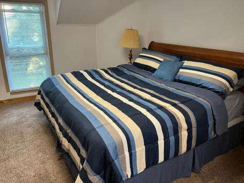 a bedroom with a bed with a striped comforter and a window at The Water Street House in Port Huron