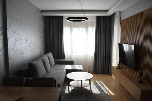 uma sala de estar com um sofá e uma mesa em Zlatibor Prestige Apartman 18 em Zlatibor