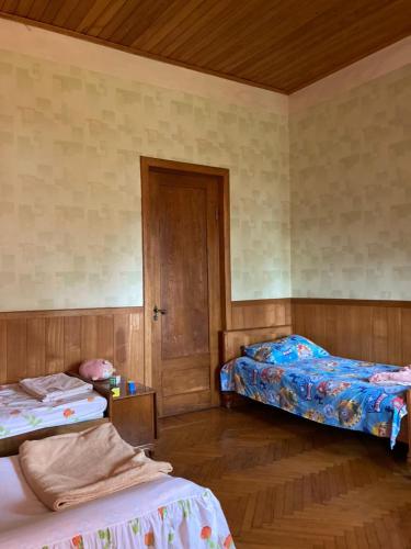 a bedroom with two beds and a wooden floor at Des Nana in Koko