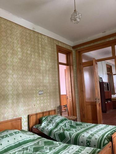 a bedroom with two beds with green comforter at Des Nana in Koko