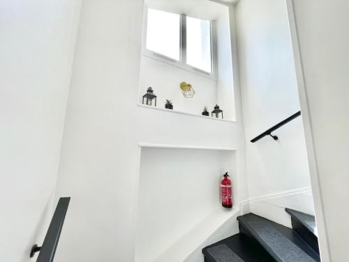 a staircase in a house with a window and a red fire hydrant at Appart Cosy Proche gare in Mantes-la-Jolie