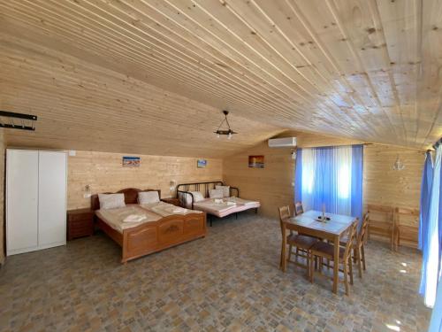 a room with two beds and a table and chairs at Pensiunea Blue House in Vadu