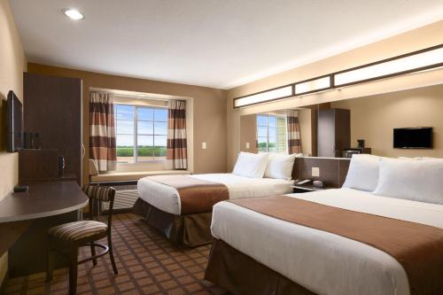 Habitación de hotel con 2 camas y escritorio en Microtel Inn & Suites Cotulla, en Cotulla