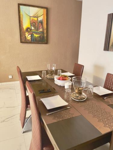 a dining room table with chairs and a painting on the wall at Apart Teranga Dakar Plateau in Dakar
