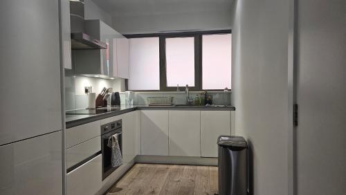 a white kitchen with a sink and a stove at Gallions Reach - One Bed Flat in Beckton