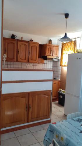 une cuisine avec des armoires en bois et un réfrigérateur blanc dans l'établissement Petite Maison au barcares 4 personnes, au Barcarès