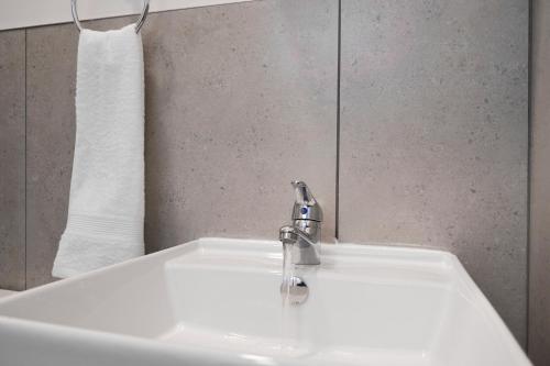 a white sink with a faucet and a towel at The Base Apartment in Johannesburg