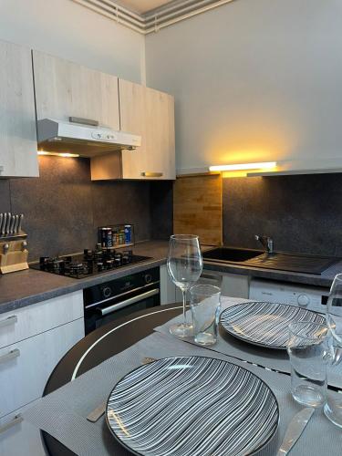 - une cuisine avec une table avec deux assiettes et des verres à vin dans l'établissement Triplex - Au cœur de Fougères, à Fougères