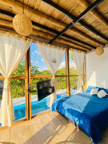 a bedroom with a blue bed and a large window at Tradición Lodge in Manizales