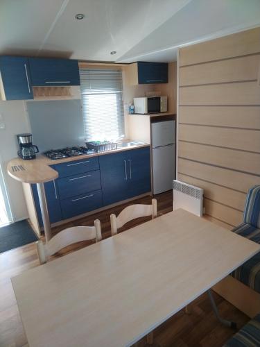 une cuisine avec des armoires bleues et une table et des chaises dans l'établissement Mobile home proche Europapark et rulantica proche allemagne, à Boofzheim