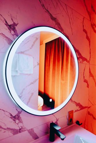 a bathroom mirror with a red curtain and a sink at Maison du Roi in Liège
