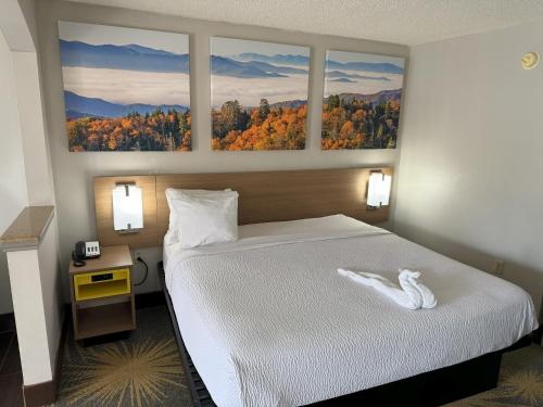 a bedroom with a bed with three paintings on the wall at Days Inn & Suites by Wyndham Tuscaloosa - Univ. of Alabama in Tuscaloosa