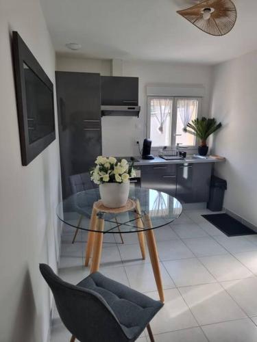 une cuisine avec une table en verre et un vase de fleurs. dans l'établissement Maison cosy aux portes de Tours, à Saint-Pierre-des-Corps