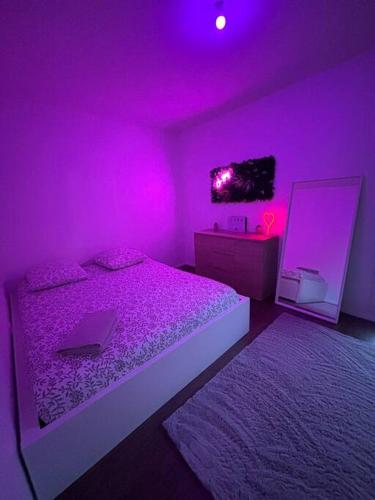 - une chambre violette avec un lit et un miroir dans l'établissement Appart Cosy, à Montfermeil