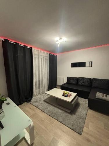 un salon avec un canapé noir et une table dans l'établissement Appart Cosy, à Montfermeil