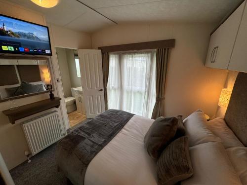 a bedroom with a large bed and a television at Golden Palm Resort - The Superior Retreat - Coastal Caravan Breaks in Chapel Saint Leonards